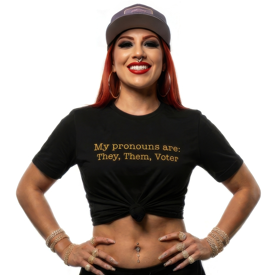 A confident person smiling 📸, wearing a black premium Bella+Canvas t-shirt with gold text reading My pronouns are: They, Them, Voter 🌟, promoting accessible voting.