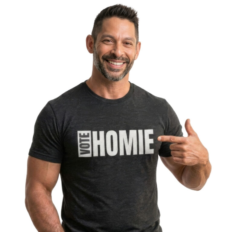 Jesse Alaniz, Executive Director of Protect November, smiling in a heather dark gray Vote Homie t-shirt pointing directly to the white block lettering on the chest against a white background.