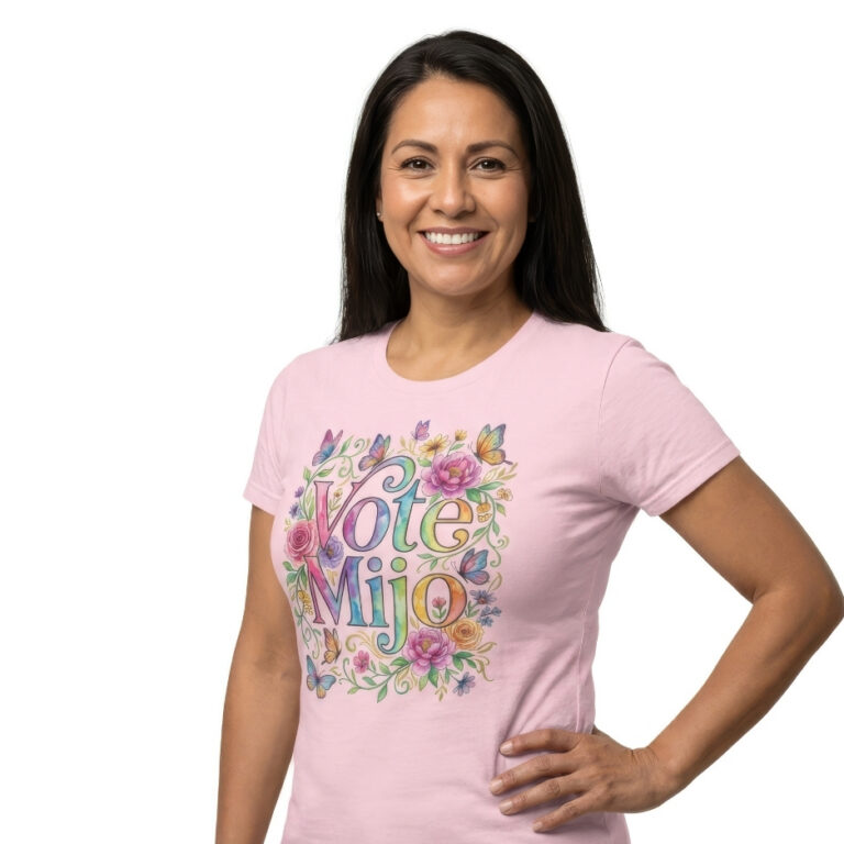 Mother wearing a pink t-shirt featuring vibrant watercolor graphic text reading Vote Mijo surrounded by colorful roses, peonies, gold accents, and butterflies.