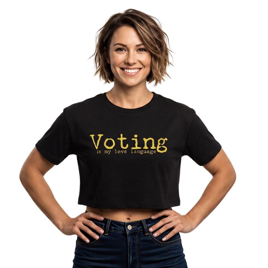 Woman wearing graphic streetwear t-shirt featuring bold, distressed yellow text that reads 'Voting is my love language' across a solid black background.