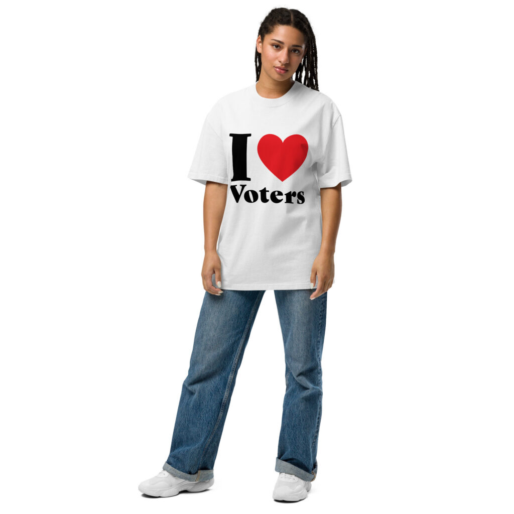 Woman wearing an oversized white t-shirt with a big red heart and black text reading I Love Voters, paired with jeans